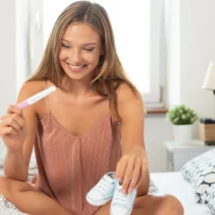 Woman on bed holding pregnancy test